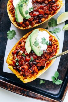 two chili stuffed sweet potatoes with avocado and sour cream