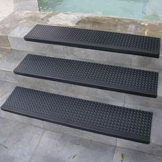 three black steps leading up to a pool with water in the backgrouds