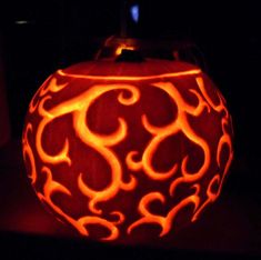 a pumpkin carved to look like the letter s is lit up in the dark with flames