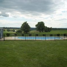 an empty swimming pool in the middle of a grassy field