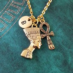 a gold plated necklace with an egyptian head and cross charm on it's link