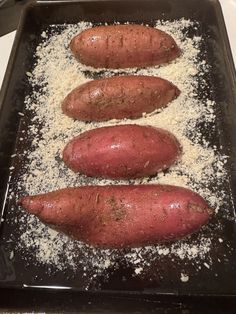 three sweet potatoes sitting on top of a baking pan covered in white powdered sugar