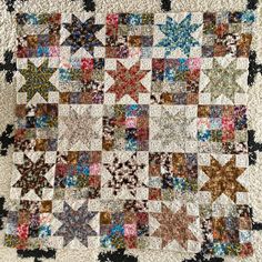 an old quilt with many different colors and designs on the front, along with several small stars