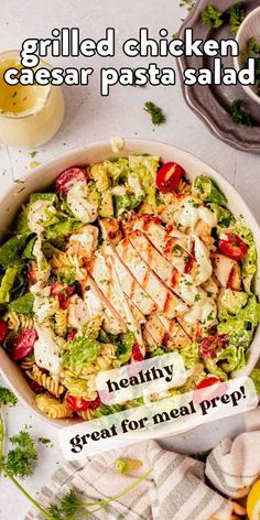 a salad with chicken, lettuce and tomatoes in it on a white table