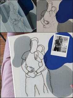 a person holding a baby in their arms next to some drawings on the back of a canvas