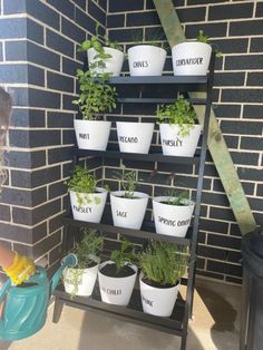 a child watering plants in front of a brick wall with words on the planters