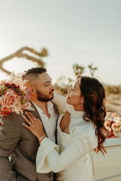 a man and woman embracing each other in front of a car with flowers on it