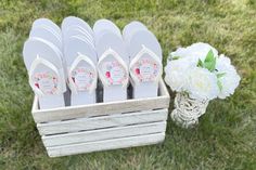 white flip flops are sitting in a basket next to flowers