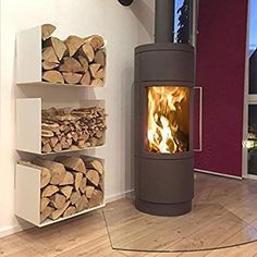 a wood burning stove sitting inside of a living room next to a stack of logs