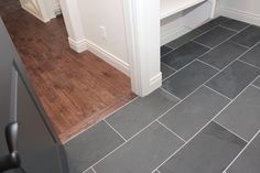 an empty kitchen with wood flooring and white cabinets on the wall, next to a gray tile floor