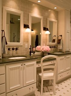 a bathroom with two sinks, mirrors and a chair in front of the sink area