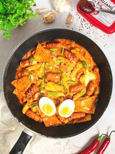 a skillet filled with meat and eggs on top of a table next to garlic