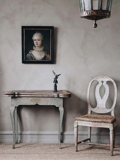 a chair and table in a room with a painting on the wall