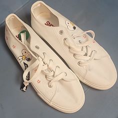 a pair of white tennis shoes with cartoon characters on the soles and laces