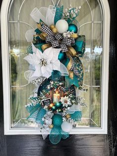 a christmas wreath on the front door with ornaments hanging from it's centerpiece