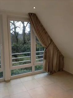 an empty room with large windows and curtains