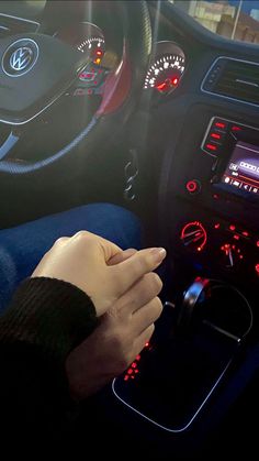 a person's hand on the steering wheel of a car with red and blue lights