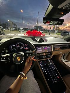 a woman driving a porsche car on the road at night with her hands on the steering wheel