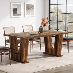 a wooden table with chairs around it in front of a large window and pictures on the wall