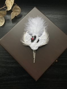 a white and black brooch sitting on top of a wooden table