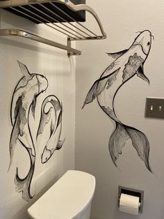 two fish drawn on the wall next to a toilet