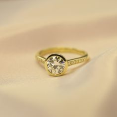 a yellow gold ring with a single diamond on the side, sitting on a white cloth