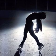 a woman skating on an ice rink in the dark