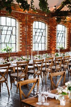 the tables and chairs are set up in front of large windows with greenery hanging from them