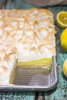 a lemon meringue pie on a wooden table next to sliced lemons