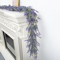 purple flowers are growing on the top of a fireplace mantel in front of a white wall