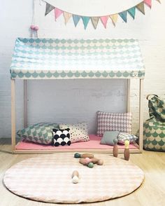 a child's bed with pillows and toys on the floor in front of it