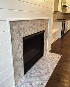 a fireplace in the middle of a room with white walls and wood flooring on either side