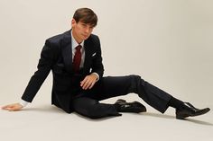 a man in a suit and tie sitting on the ground