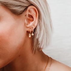 a woman with blonde hair wearing gold earrings