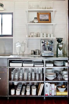 a kitchen with stainless steel cabinets and shelves filled with dishes, cups, and utensils