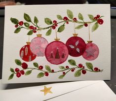 a christmas card with ornaments hanging from it