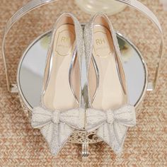 a pair of silver high heel shoes sitting on top of a glass table next to a mirror