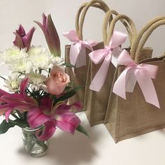 three bags with pink and white flowers in them sitting on a table next to each other