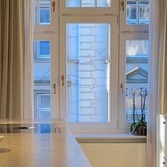 an empty kitchen with white counter tops and curtains on the window sill, next to a sink