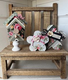 a wooden bench topped with lots of paper flowers next to a small house shaped like a birdhouse