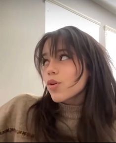 a woman with long black hair is looking off into the distance while wearing a turtle neck sweater