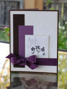 a thank you card with purple ribbon and flowers on the front, sitting on a window sill