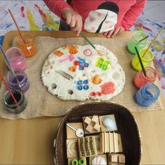 a child is painting on a piece of paper with wooden blocks and paintbrushes