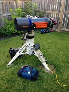 a telescope sitting on top of a green field next to a blue and orange object