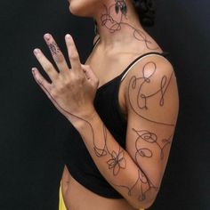 a woman with tattoos on her arms and chest holding up her hand in front of her face