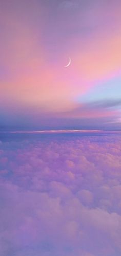 an airplane wing flying above the clouds at dusk with a half moon in the sky