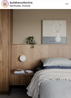 a bed sitting next to a wooden wall with a painting on the wall above it