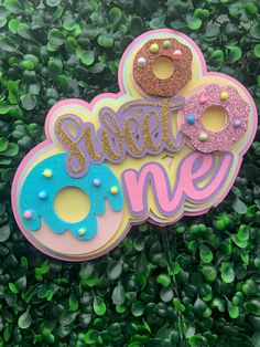 there is a sign that says sweet one with donuts on it and sprinkles