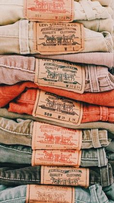 many different colored shirts are stacked on top of each other, with labels reading quality clothing