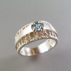 a white gold ring with a blue topazte stone in the center and two silver bands around it